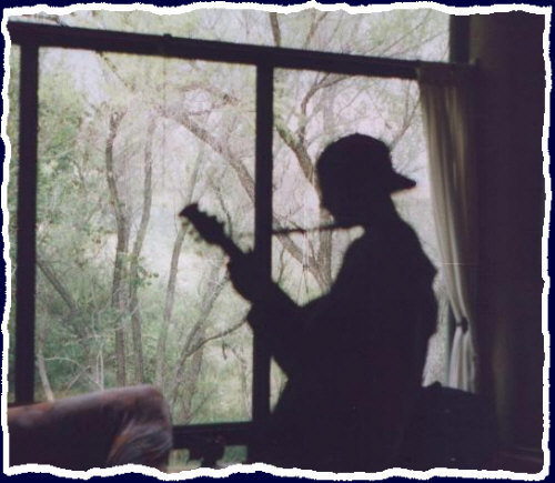 The silhouette of Jarod with the back yard creek in the background